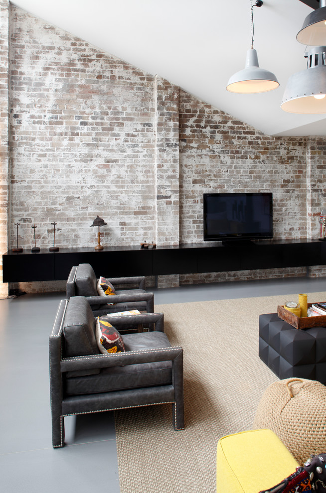 Photo of a large industrial open concept living room in Sydney with concrete floors and a freestanding tv.