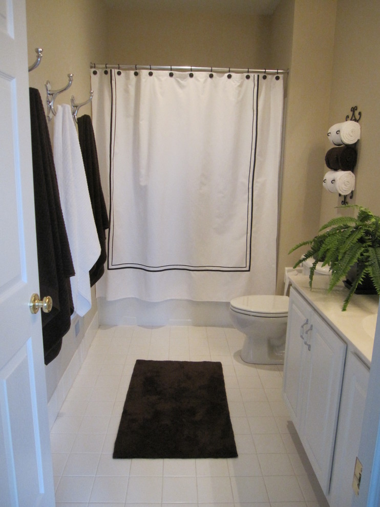 Photo of a small traditional master bathroom in Philadelphia with raised-panel cabinets, white cabinets, a drop-in tub, a double shower, a two-piece toilet, white tile, ceramic tile, beige walls, ceramic floors, an integrated sink and solid surface benchtops.