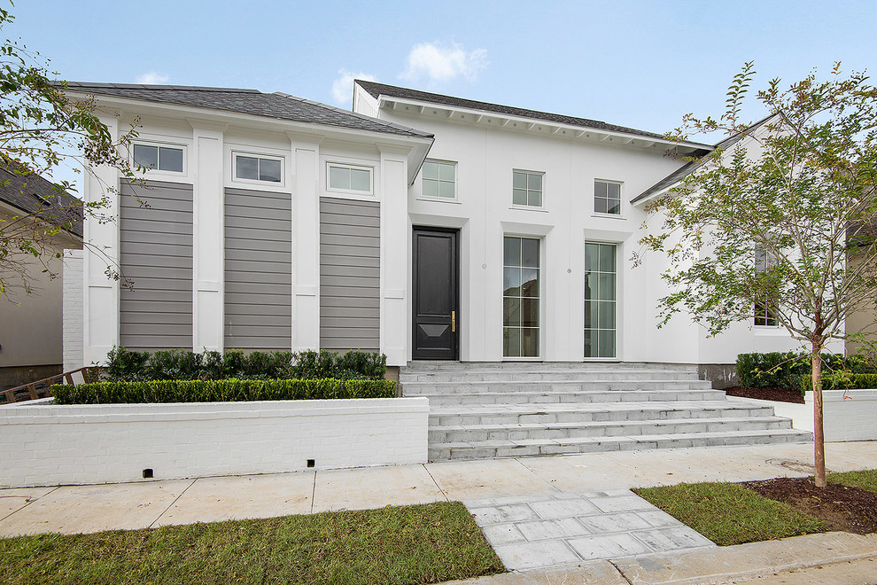 Photo of a mid-sized transitional two-storey stucco white house exterior in New Orleans with a hip roof and a shingle roof.