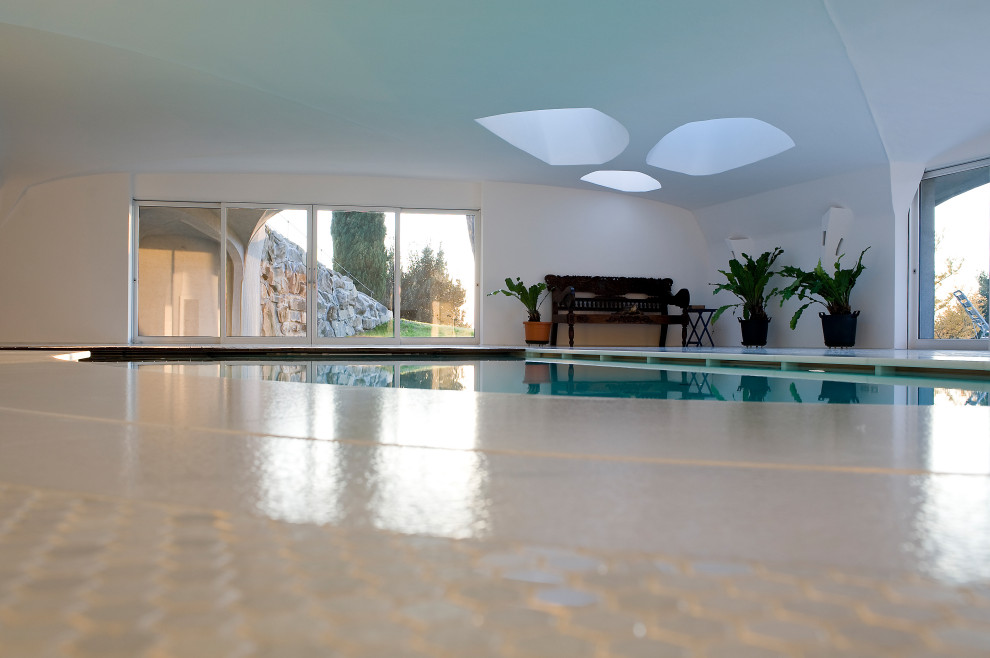Immagine di una grande piscina coperta design personalizzata con piastrelle