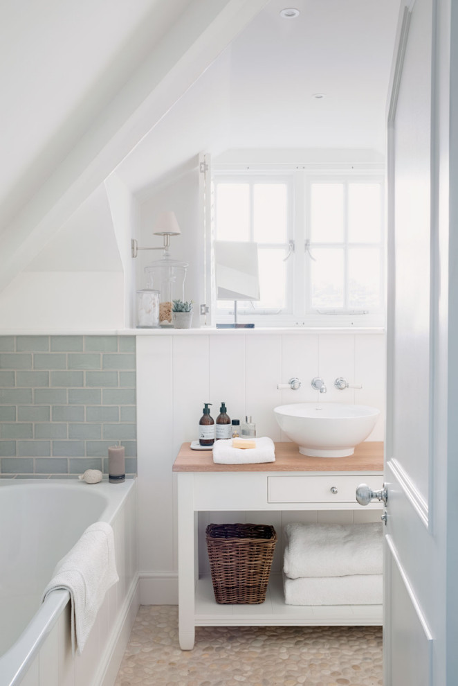 Inspiration for a small beach style master bathroom in Other with white walls, pebble tile floors, wood benchtops, beige floor, brown benchtops, white cabinets, an alcove tub, green tile, subway tile, a vessel sink and flat-panel cabinets.