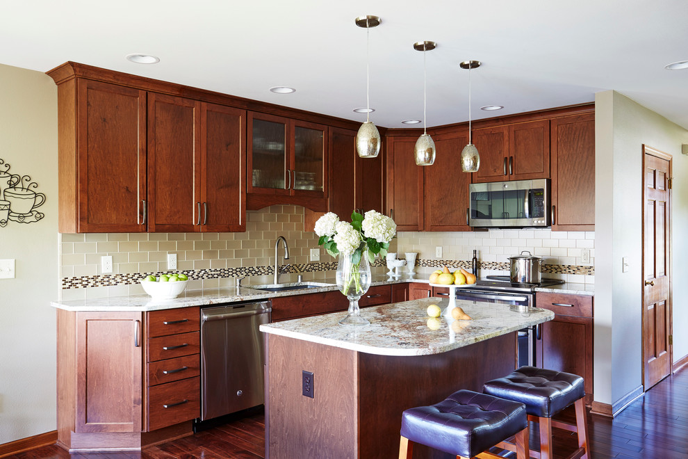 Example of a large transitional l-shaped medium tone wood floor enclosed kitchen design in Milwaukee with an undermount sink, shaker cabinets, medium tone wood cabinets, granite countertops, beige backsplash, glass tile backsplash, stainless steel appliances and an island