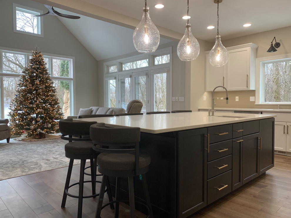 Kitchen - large transitional l-shaped medium tone wood floor kitchen idea in Milwaukee with recessed-panel cabinets, black cabinets, quartz countertops, beige backsplash, an island and white countertops