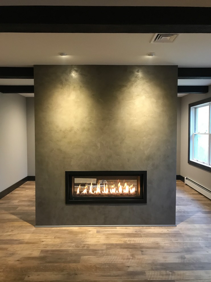 Photo of a large country master bedroom in Philadelphia with a two-sided fireplace, grey walls, medium hardwood floors and brown floor.