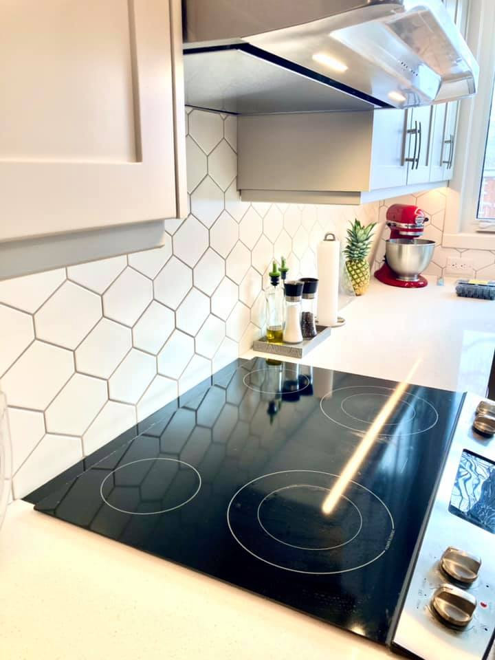Enclosed kitchen - mid-sized transitional u-shaped vinyl floor and gray floor enclosed kitchen idea with an undermount sink, shaker cabinets, beige cabinets, quartz countertops, white backsplash, ceramic backsplash, stainless steel appliances and white countertops