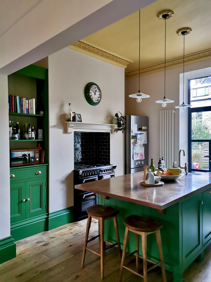 Inredning av ett klassiskt mellanstort brun brunt kök och matrum, med en rustik diskho, skåp i shakerstil, gröna skåp, bänkskiva i akrylsten, grönt stänkskydd, stänkskydd i keramik, integrerade vitvaror, mellanmörkt trägolv, en köksö och brunt golv
