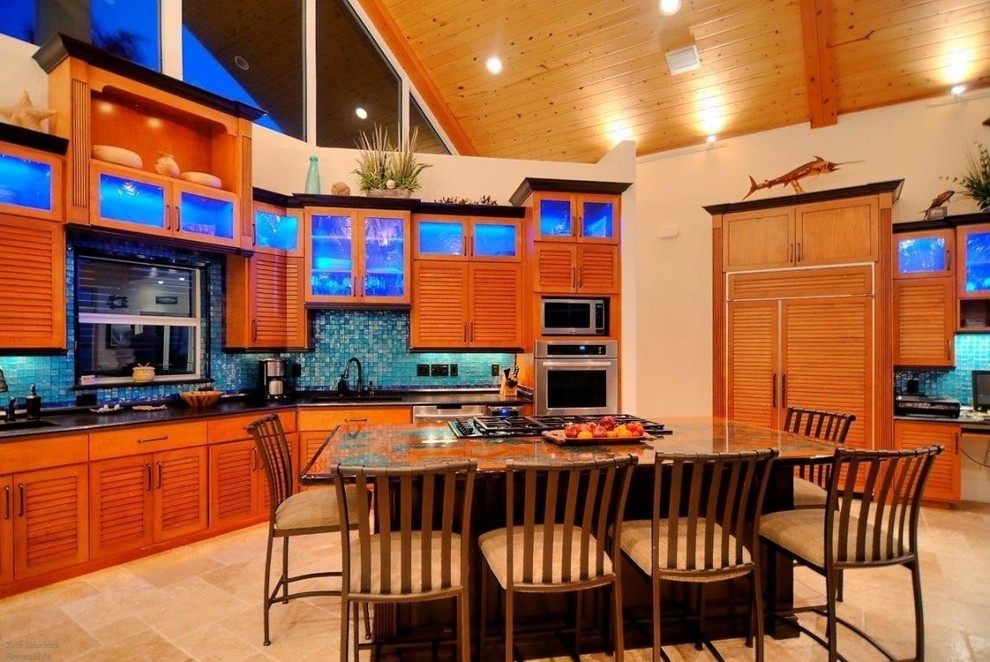 Inspiration for a mid-sized tropical u-shaped open plan kitchen in Orlando with an undermount sink, louvered cabinets, medium wood cabinets, granite benchtops, blue splashback, mosaic tile splashback, stainless steel appliances, limestone floors and with island.