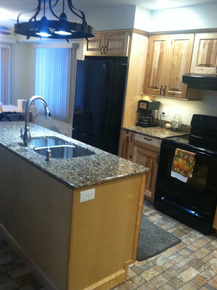 Mid-sized mountain style l-shaped ceramic tile eat-in kitchen photo with an undermount sink, raised-panel cabinets, light wood cabinets, quartz countertops, black appliances and an island