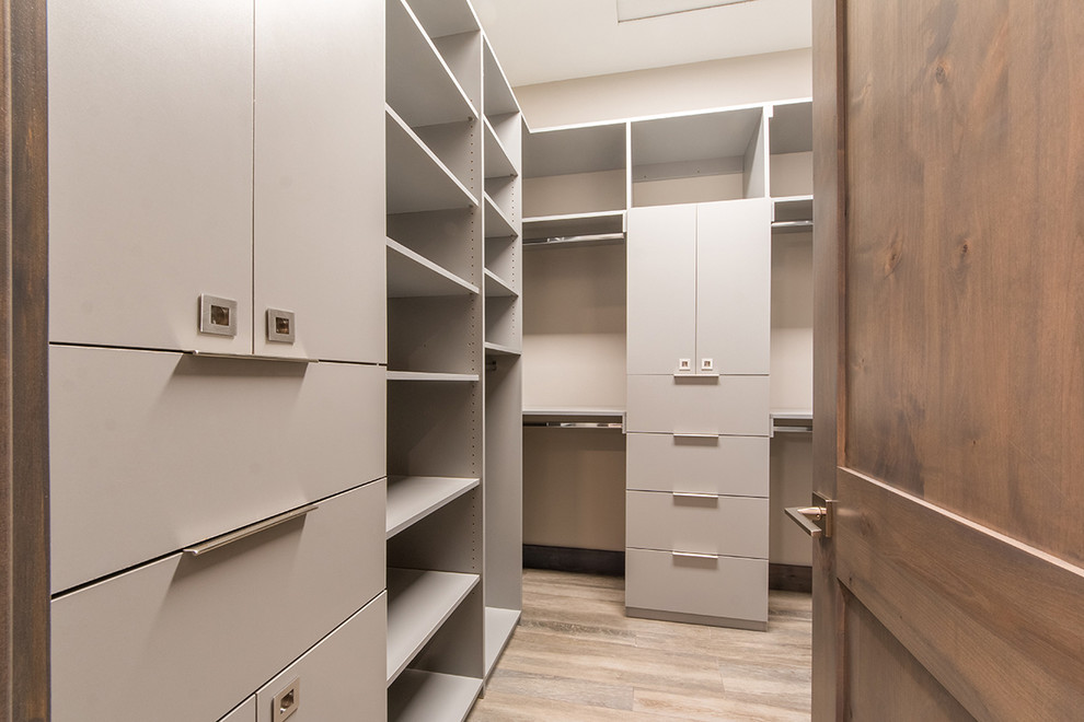 Mid-sized contemporary gender-neutral walk-in wardrobe in San Diego with flat-panel cabinets, grey cabinets, laminate floors and brown floor.