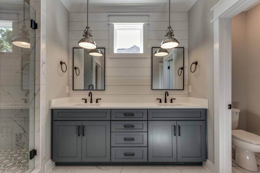 Photo of a master bathroom in Nashville with shaker cabinets, blue cabinets, an alcove shower, a two-piece toilet, white tile, porcelain tile, marble floors, an undermount sink, engineered quartz benchtops, a hinged shower door, white benchtops, a double vanity and a built-in vanity.