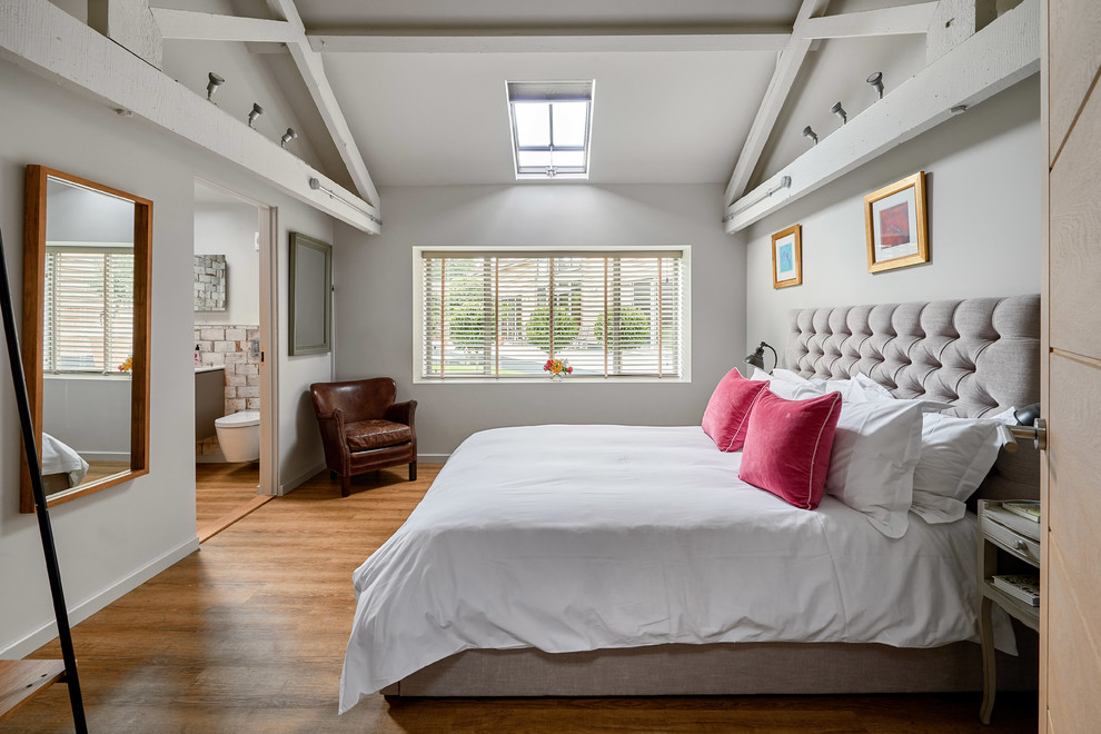 This is an example of a mid-sized country guest bedroom in Hampshire with grey walls, dark hardwood floors and brown floor.