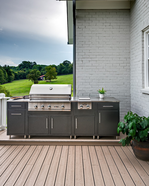 Outdoor stainless steel grill with dark powder-coated aluminum kitchen cabinets on a modern deck