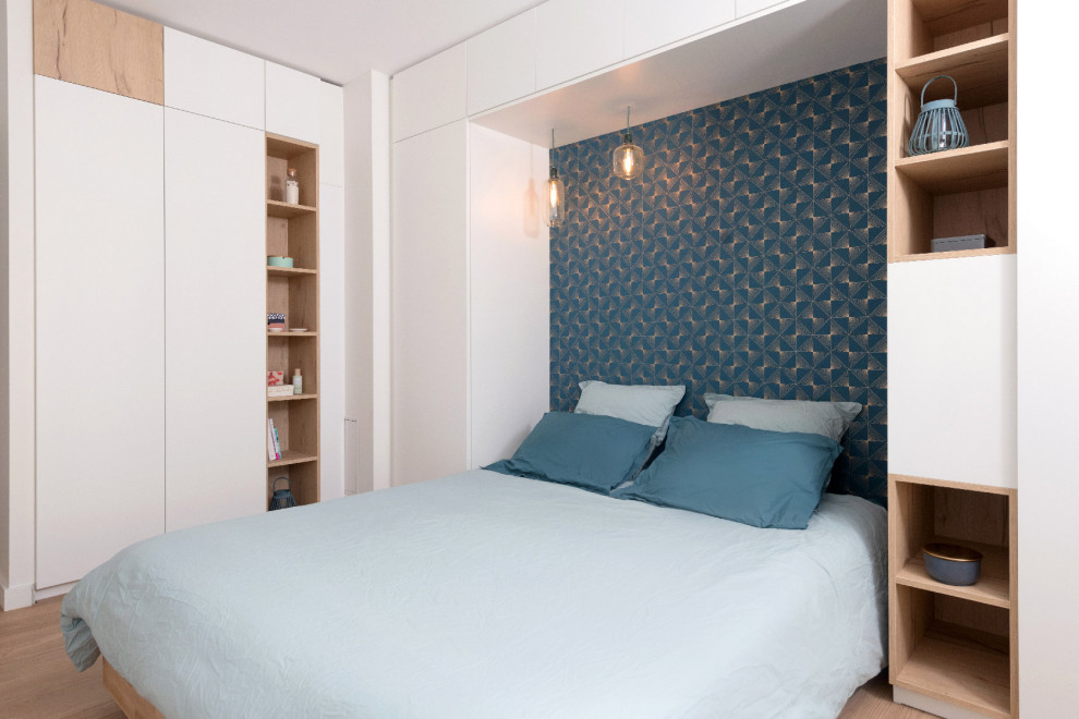 Modelo de dormitorio principal y blanco y madera actual de tamaño medio con paredes azules, suelo de madera clara y madera