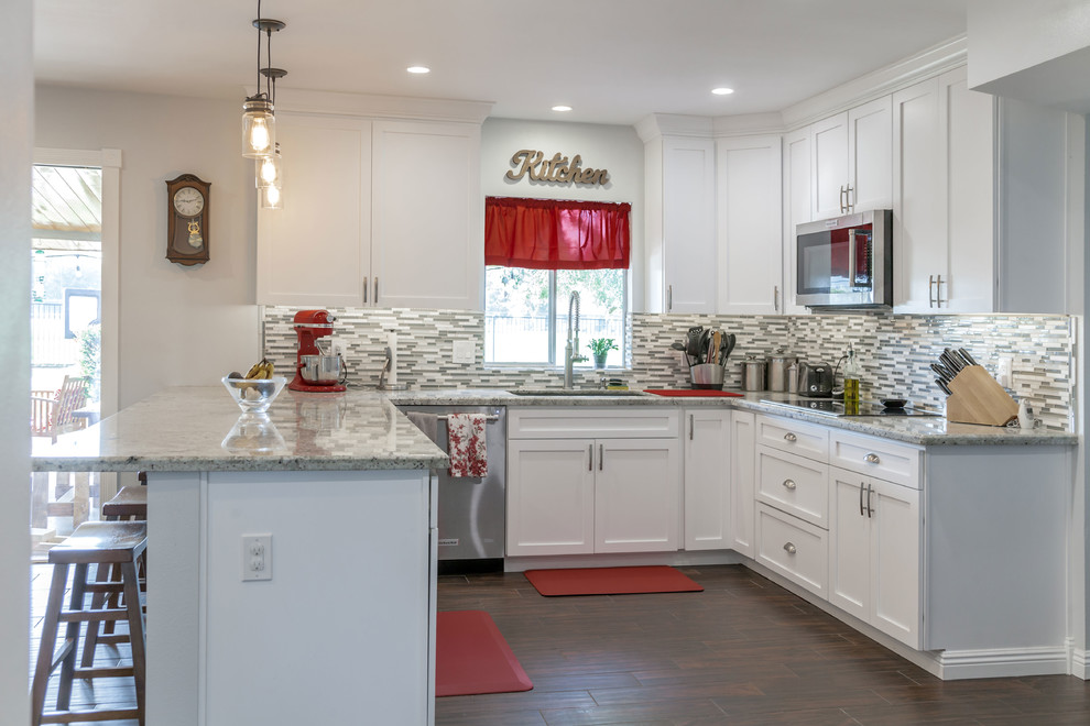 Mid-sized transitional u-shaped laminate floor and brown floor open concept kitchen photo in Phoenix with an undermount sink, recessed-panel cabinets, white cabinets, granite countertops, multicolored backsplash, mosaic tile backsplash and stainless steel appliances