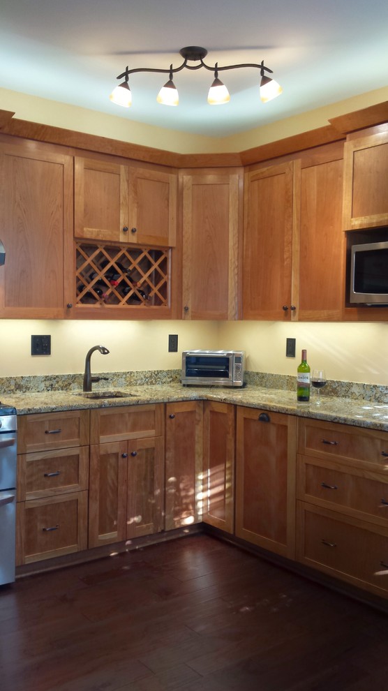 Inspiration for a mid-sized dark wood floor eat-in kitchen remodel with a single-bowl sink, flat-panel cabinets, medium tone wood cabinets, granite countertops and stainless steel appliances