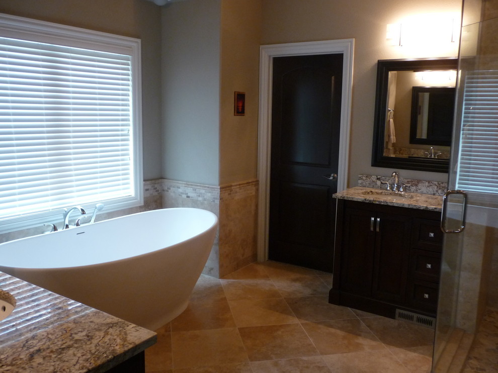 Design ideas for a large traditional master bathroom in Milwaukee with an undermount sink, flat-panel cabinets, dark wood cabinets, granite benchtops, a freestanding tub, a corner shower, a two-piece toilet, beige tile, stone tile, brown walls and marble floors.