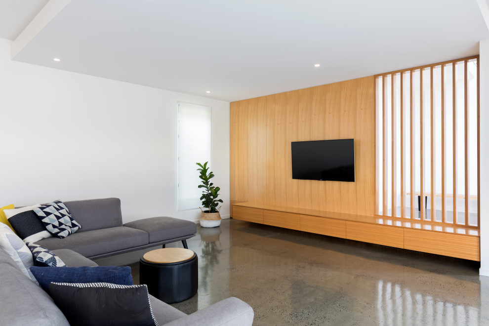 Ejemplo de salón abierto nórdico sin chimenea con paredes blancas, suelo de cemento, televisor colgado en la pared y suelo gris