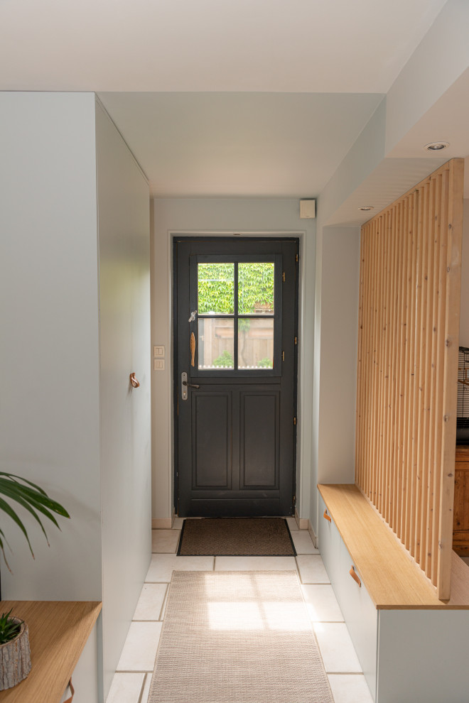Inredning av en mellanstor foajé, med blå väggar, en enkeldörr, en grå dörr och vitt golv