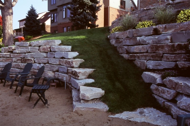 Large traditional backyard partial sun garden in Detroit with a retaining wall and natural stone pavers.