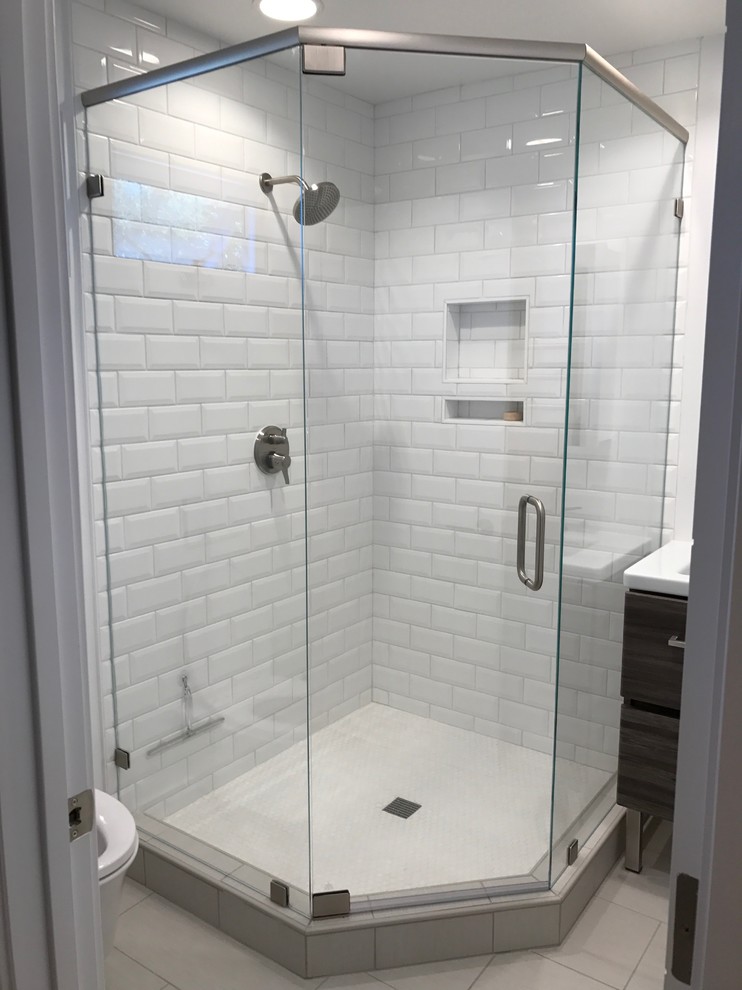 Photo of a mid-sized transitional master bathroom in San Francisco with flat-panel cabinets, medium wood cabinets, a corner shower, a one-piece toilet, white tile, subway tile, white walls, porcelain floors, an integrated sink, engineered quartz benchtops, beige floor, a hinged shower door and white benchtops.