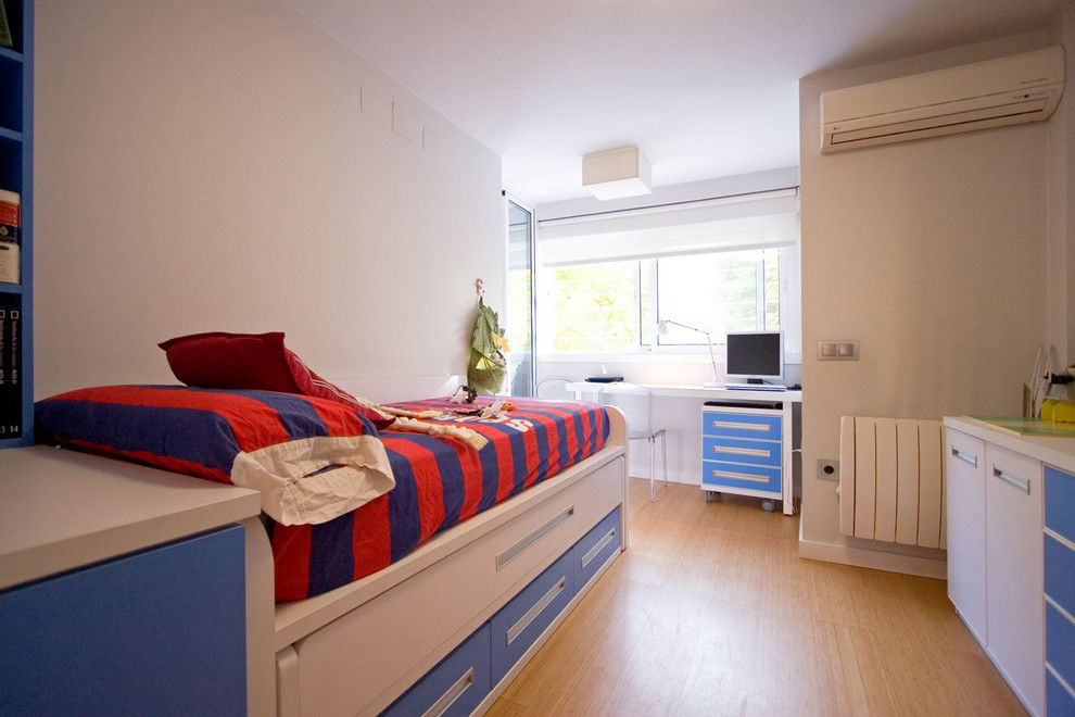 This is an example of a mid-sized contemporary kids' bedroom for kids 4-10 years old and boys in Seville with white walls and medium hardwood floors.