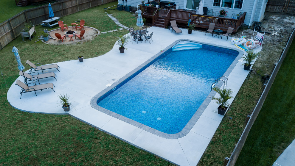 Inspiration pour un grand piscine avec aménagement paysager arrière traditionnel rectangle avec une dalle de béton.