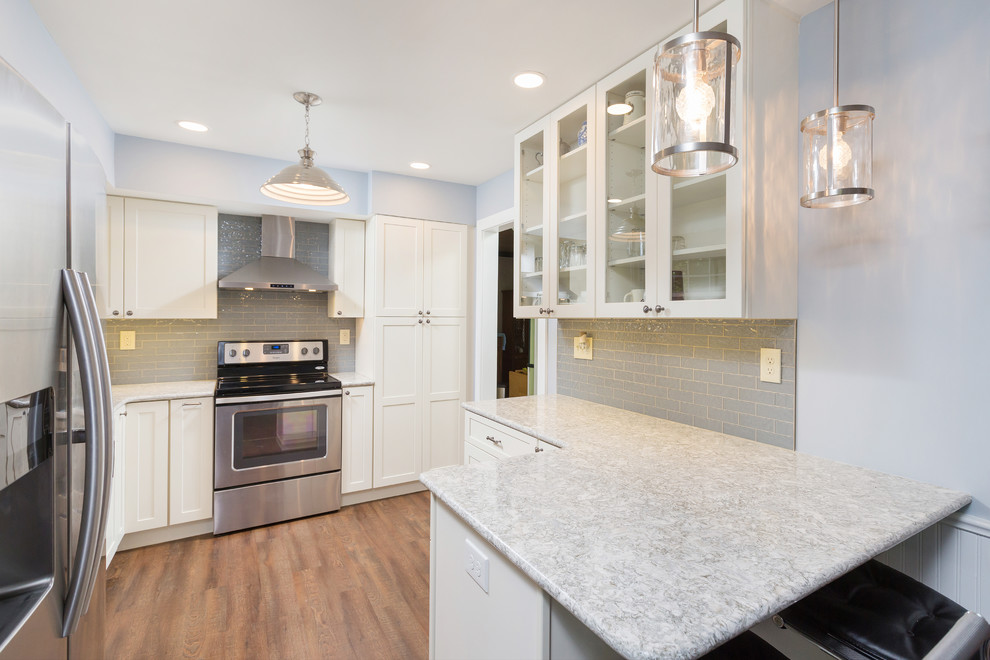 Design ideas for a small contemporary kitchen in Philadelphia with an undermount sink, glass-front cabinets, white cabinets, quartzite benchtops, grey splashback, subway tile splashback, stainless steel appliances, vinyl floors, brown floor and grey benchtop.