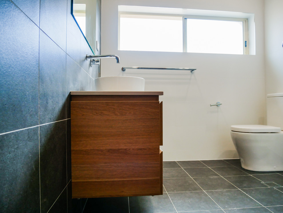 Photo of a mid-sized contemporary bathroom in Sydney with a corner shower, a one-piece toilet, gray tile, ceramic tile, ceramic floors, a wall-mount sink, grey floor and a hinged shower door.