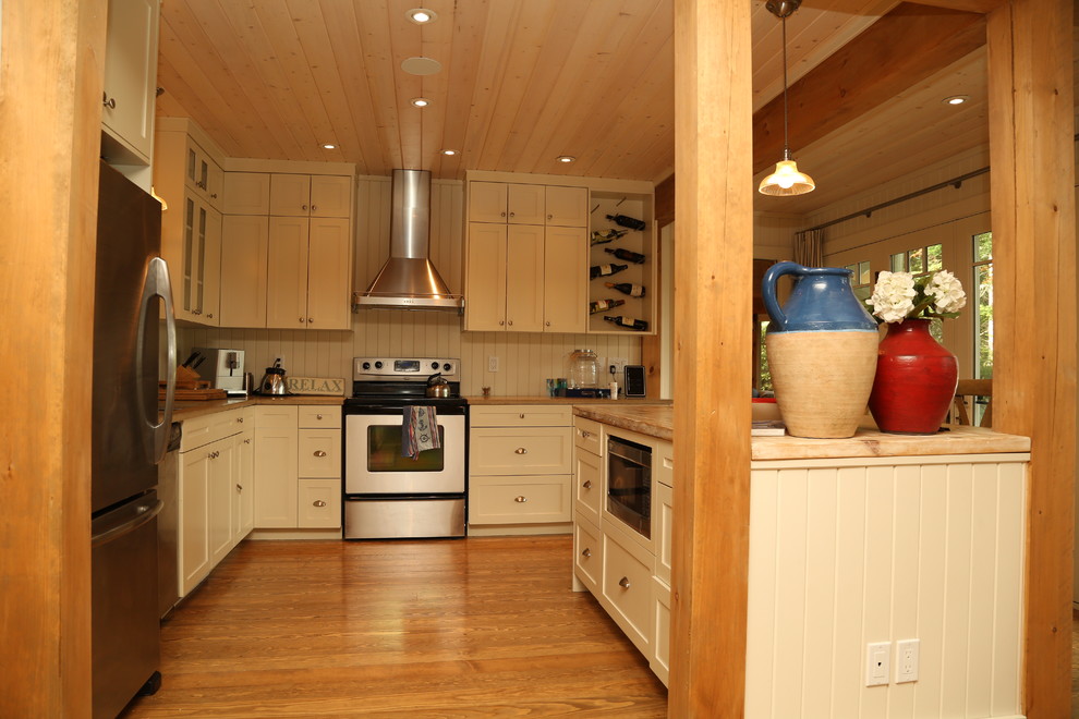 Example of a mid-sized arts and crafts l-shaped medium tone wood floor eat-in kitchen design with an undermount sink, shaker cabinets, white cabinets, quartz countertops, white backsplash, stainless steel appliances and an island