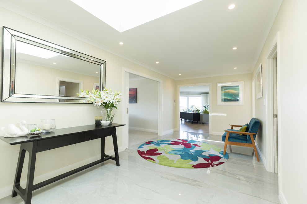 This is an example of a large contemporary entryway in Auckland with white walls, porcelain floors, a pivot front door, a metal front door and beige floor.