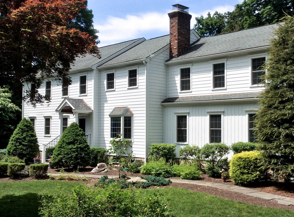 This is an example of a mid-sized traditional two-storey white house exterior in New York with vinyl siding.