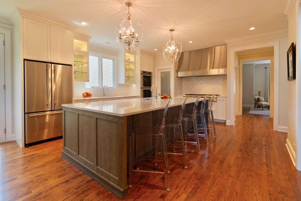 Inspiration for a large transitional l-shaped medium tone wood floor and brown floor eat-in kitchen remodel in Chicago with an undermount sink, shaker cabinets, white cabinets, quartz countertops, white backsplash, mosaic tile backsplash, stainless steel appliances, an island and white countertops