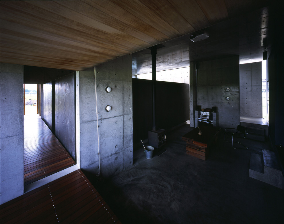 他の地域にあるモダンスタイルのおしゃれなリビング (コンクリートの床、薪ストーブ、黒い床) の写真