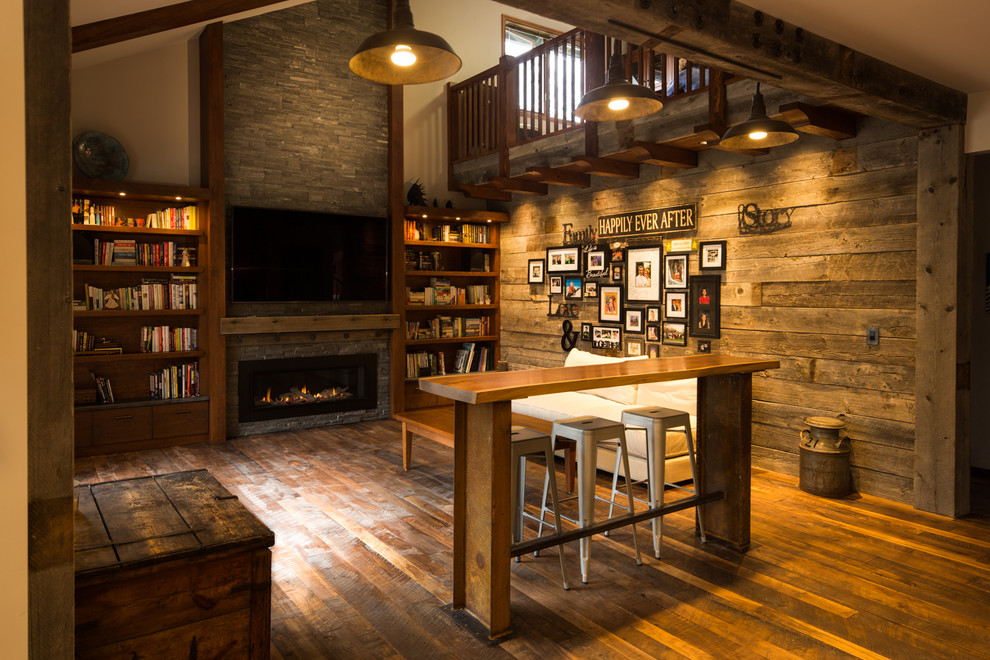 This is an example of a mid-sized country loft-style living room in Other with a home bar, grey walls, dark hardwood floors, a ribbon fireplace, a stone fireplace surround and a built-in media wall.