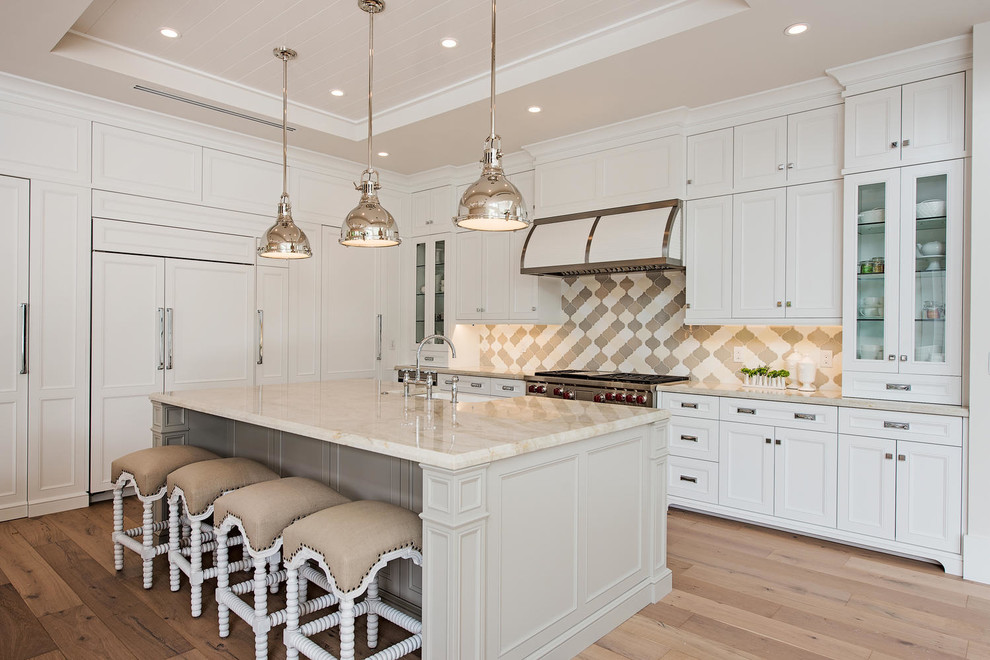 Kitchen - transitional l-shaped light wood floor and brown floor kitchen idea in Miami with shaker cabinets, white cabinets, gray backsplash, mosaic tile backsplash, paneled appliances, an island and beige countertops