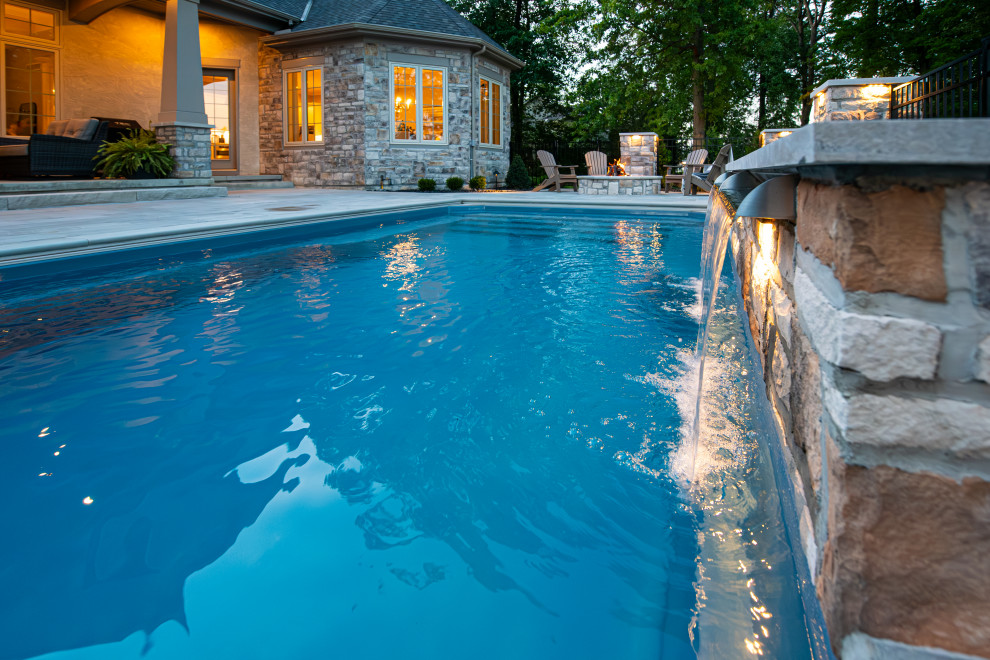 Immagine di una piscina monocorsia minimal rettangolare di medie dimensioni e dietro casa con fontane e pavimentazioni in pietra naturale