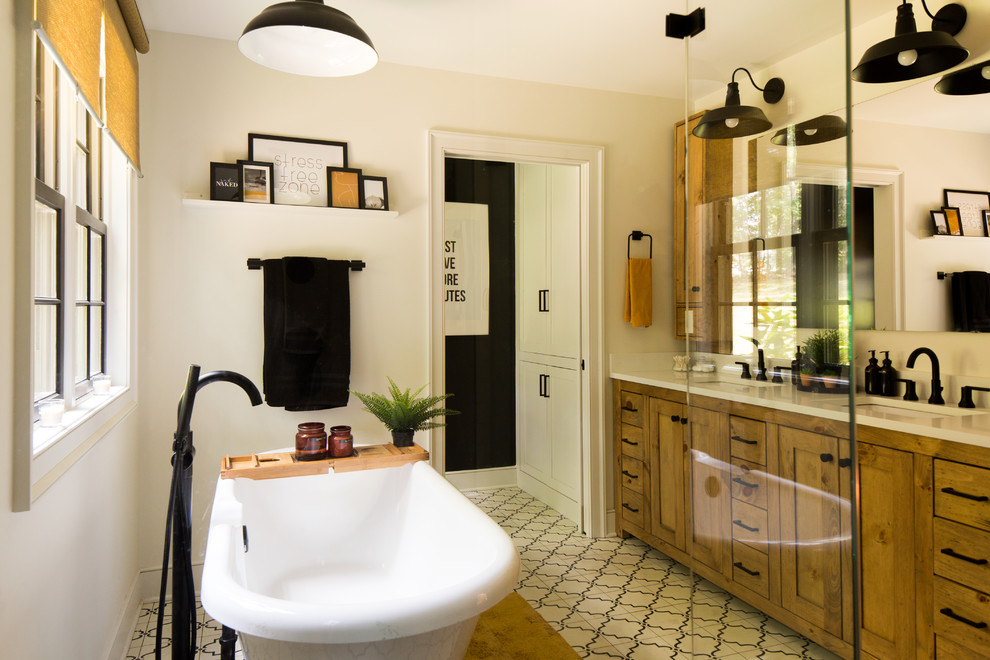 This is an example of a large transitional master bathroom in Raleigh with shaker cabinets, medium wood cabinets, a claw-foot tub, an open shower, a two-piece toilet, white tile, white walls, cement tiles, an undermount sink, limestone benchtops, white floor, a hinged shower door and white benchtops.