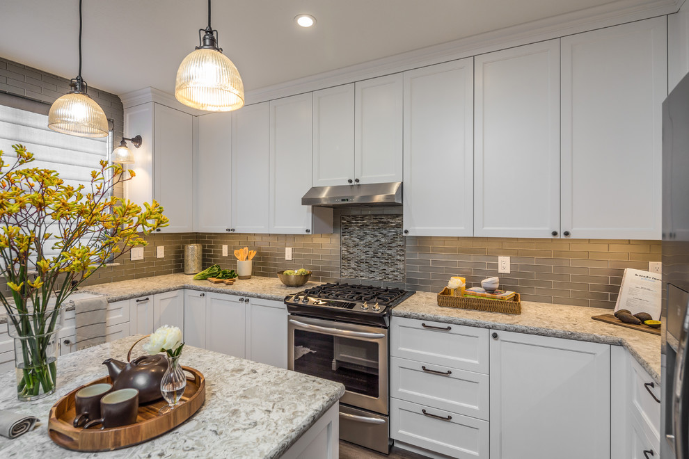 This is an example of a mid-sized transitional l-shaped eat-in kitchen in San Francisco with an undermount sink, shaker cabinets, white cabinets, quartz benchtops, grey splashback, ceramic splashback, stainless steel appliances, porcelain floors, with island, brown floor and multi-coloured benchtop.