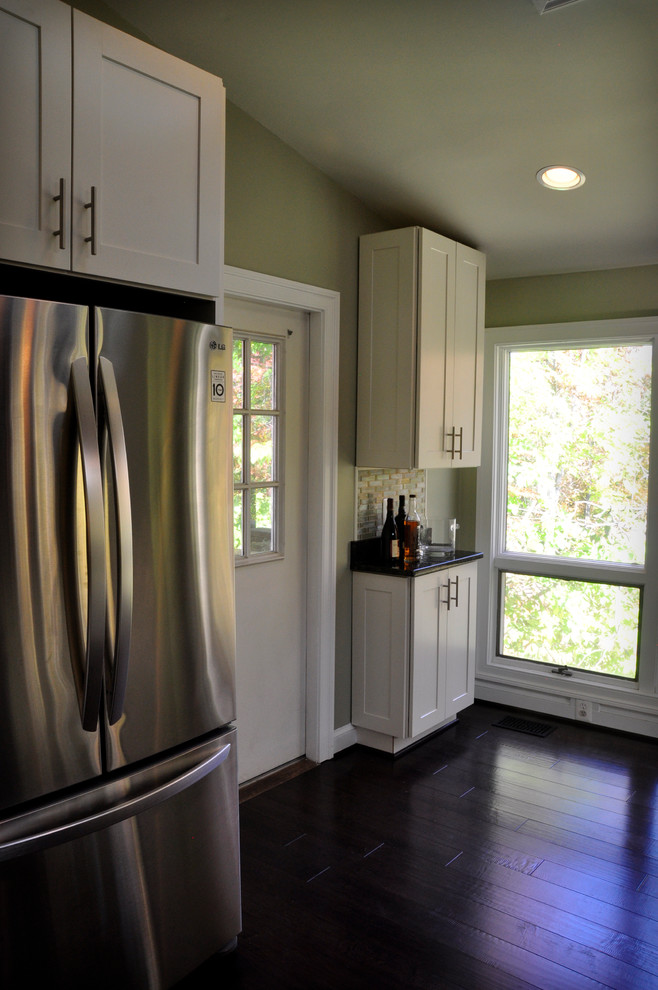 Mid-sized transitional u-shaped dark wood floor eat-in kitchen photo in DC Metro with an undermount sink, shaker cabinets, white cabinets, granite countertops, yellow backsplash, glass tile backsplash, stainless steel appliances and a peninsula