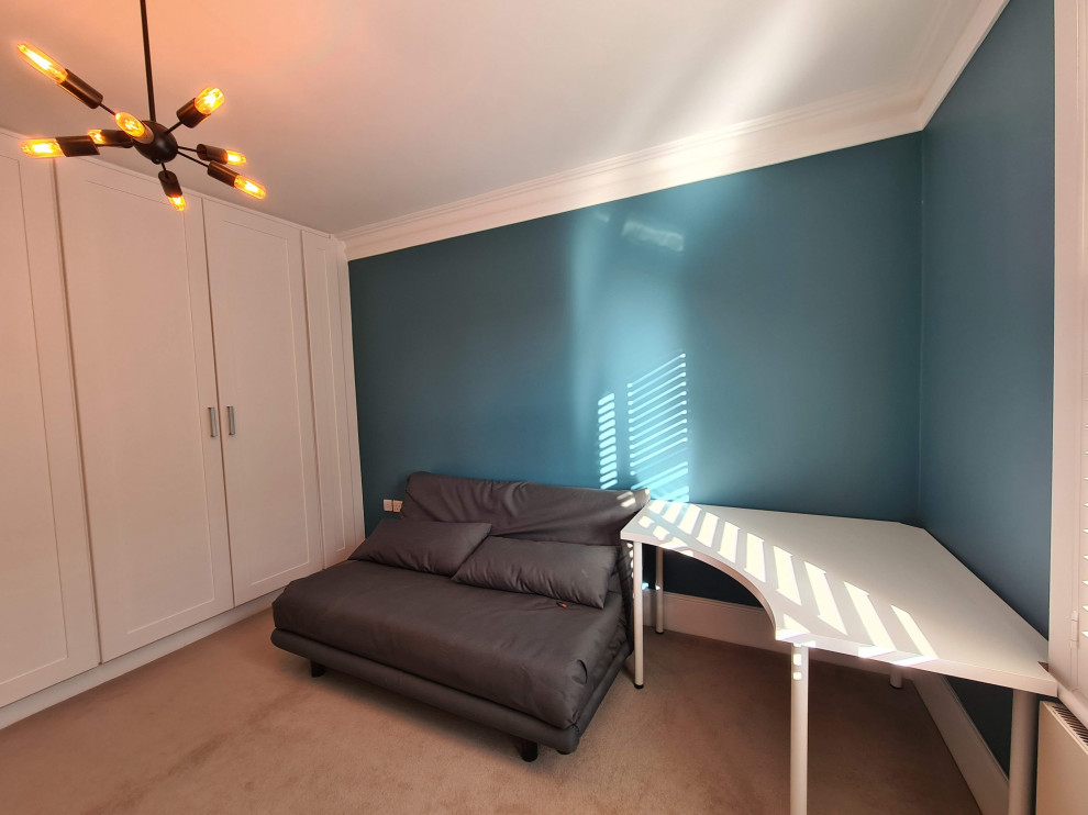 Modern inredning av ett mellanstort hemmastudio, med blå väggar, heltäckningsmatta, ett fristående skrivbord och beiget golv