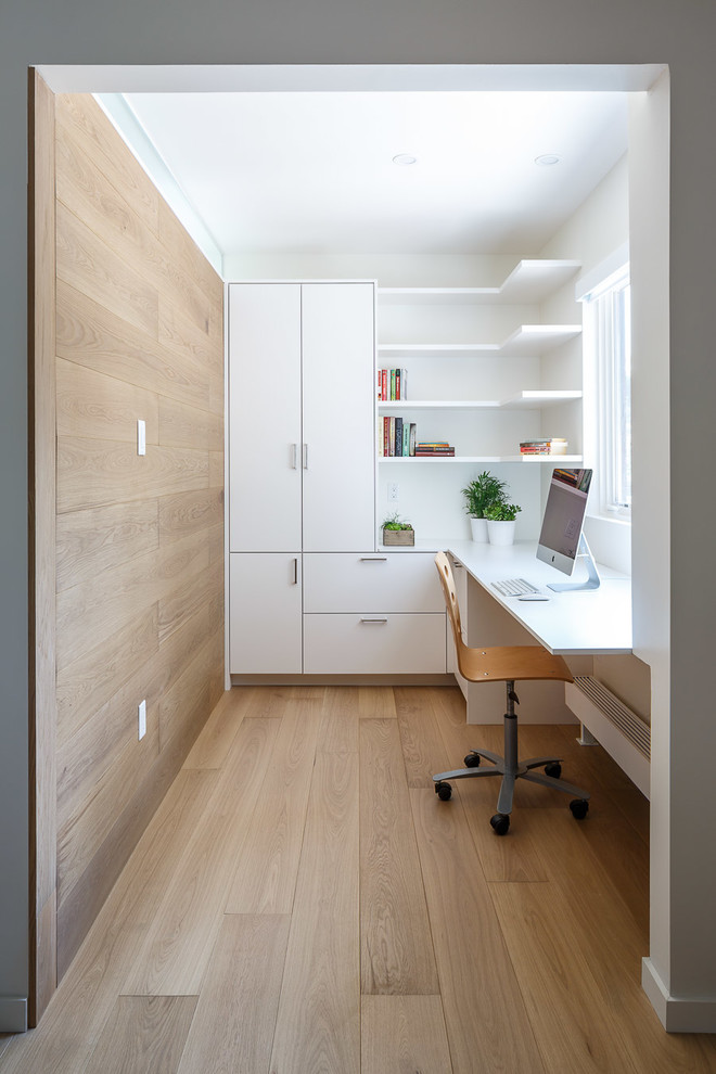 Design ideas for a mid-sized modern study room in Ottawa with white walls, light hardwood floors, a built-in desk and beige floor.