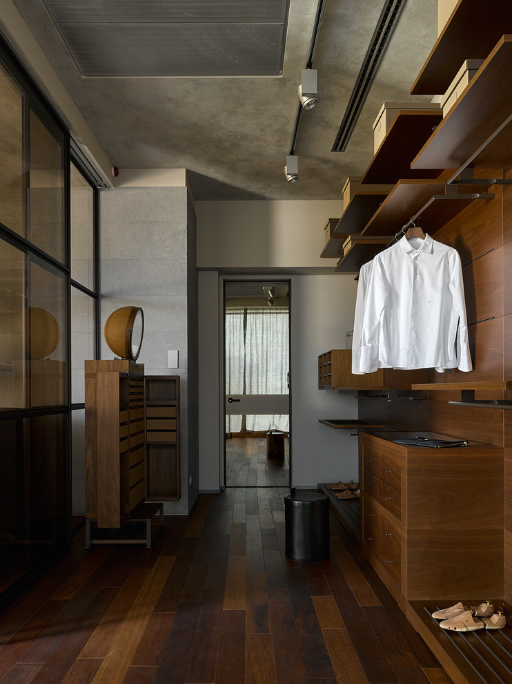 This is an example of a contemporary men's dressing room in Moscow with flat-panel cabinets, dark wood cabinets, dark hardwood floors and brown floor.