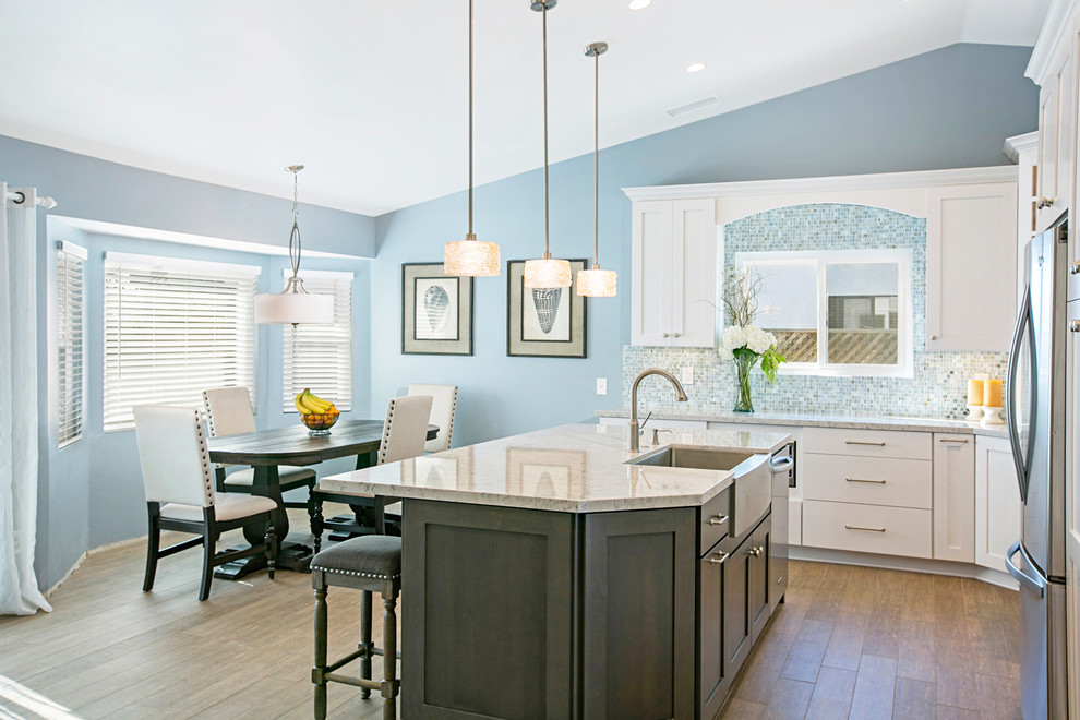 Inspiration for a large beach style kitchen in San Diego with a farmhouse sink, recessed-panel cabinets, dark wood cabinets, quartz benchtops, blue splashback, glass tile splashback, stainless steel appliances, ceramic floors and with island.