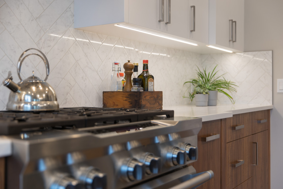 Eat-in kitchen - large transitional l-shaped light wood floor and brown floor eat-in kitchen idea in Calgary with an undermount sink, flat-panel cabinets, white backsplash, stainless steel appliances, an island and white countertops