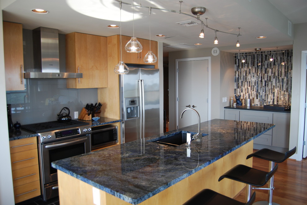 Small transitional galley medium tone wood floor open concept kitchen photo in Austin with an undermount sink, flat-panel cabinets, light wood cabinets, granite countertops, gray backsplash, porcelain backsplash, stainless steel appliances and an island