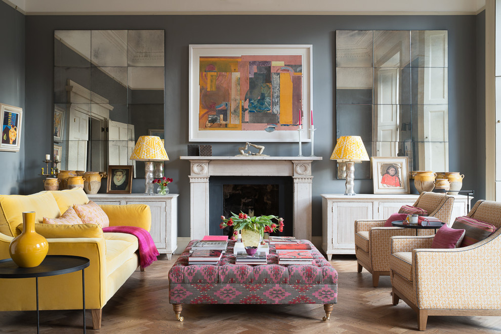 Photo of an eclectic formal living room in London with grey walls, light hardwood floors, a standard fireplace and beige floor.