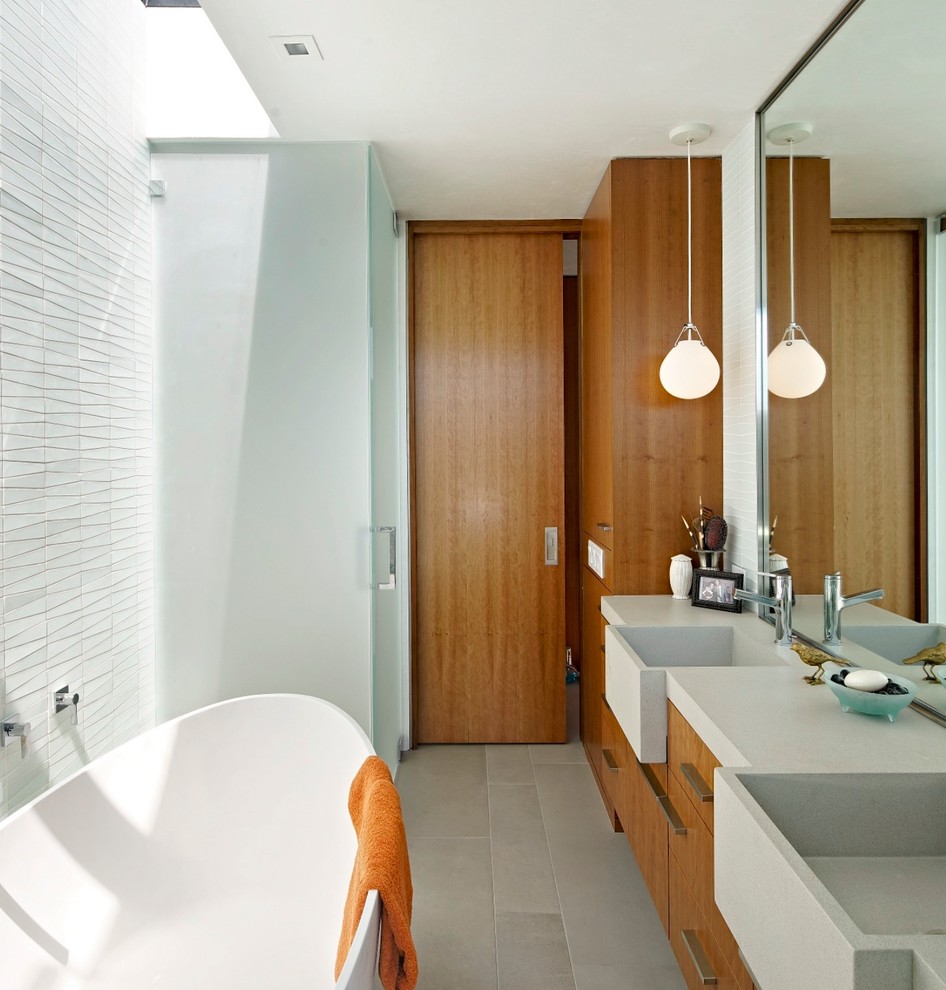 This is an example of a mid-sized midcentury master bathroom in San Francisco with flat-panel cabinets, a freestanding tub, a curbless shower, white tile, grey floor, a hinged shower door, brown cabinets, grey walls, cement tiles, an integrated sink, engineered quartz benchtops and beige benchtops.