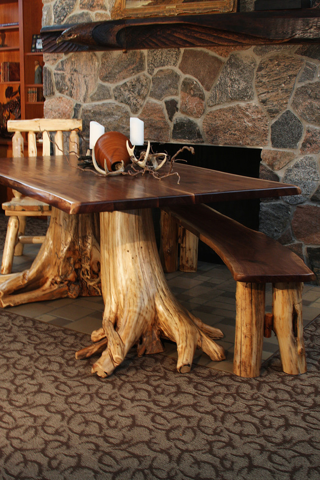 Mid-sized mountain style carpeted enclosed dining room photo with brown walls, a standard fireplace and a stone fireplace