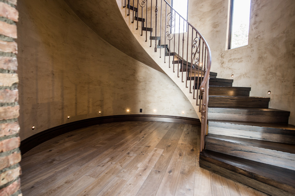 Large mediterranean wood spiral staircase in Vancouver with wood risers and metal railing.