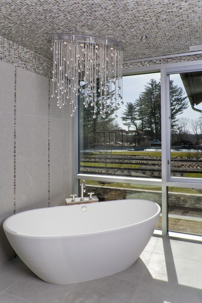 This is an example of a contemporary bathroom in New York with a freestanding tub and mosaic tile.